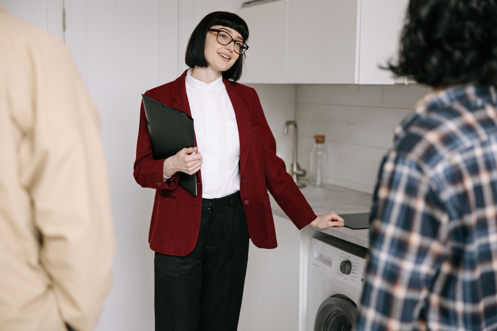 Real estate agent with clients in a modern kitchen during apartment viewing. Professional and engaging