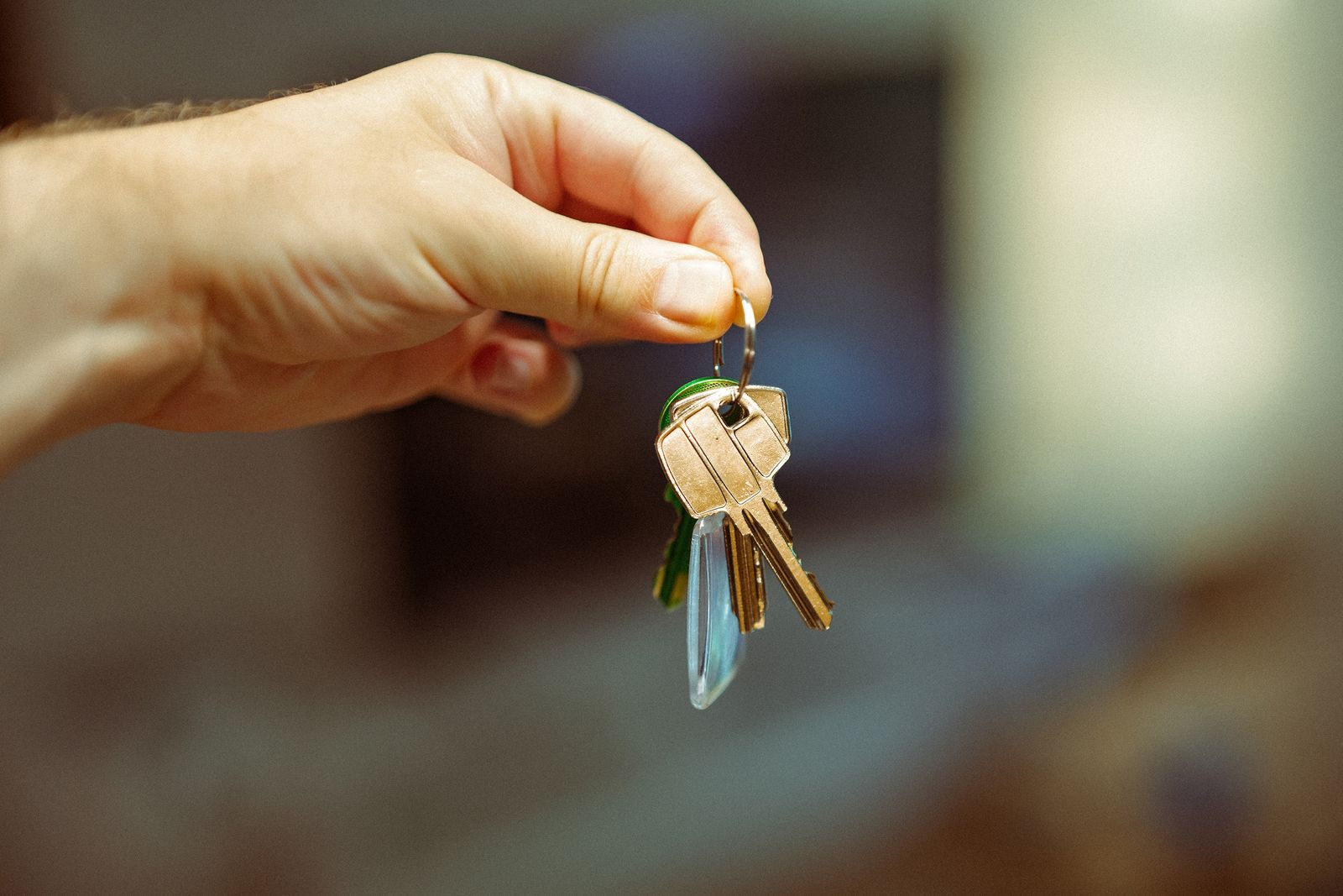 A close-up image of a hand holding a keyring with several house keys, symbolizing real estate and home ownership